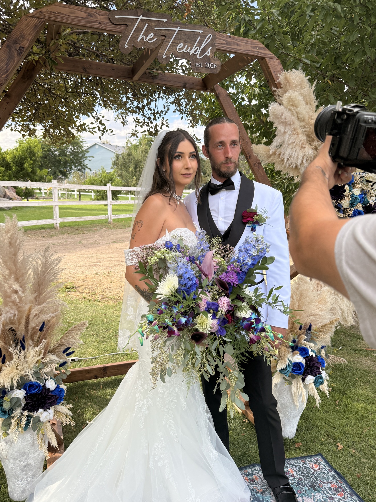 Newlyweds photographed beneath a flower-covered wooden arbor
