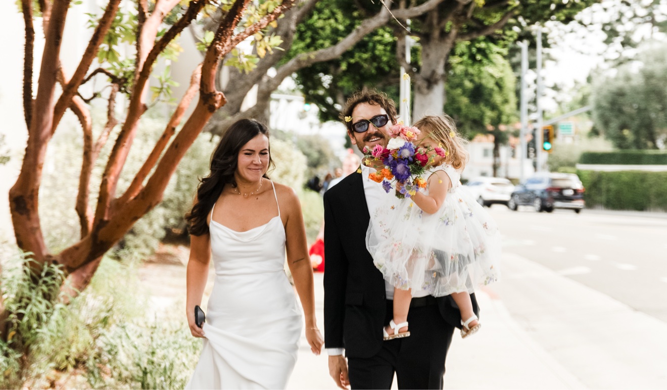 Wedding couple walking on a Beverly Hills street with a small child carrying the bouquet