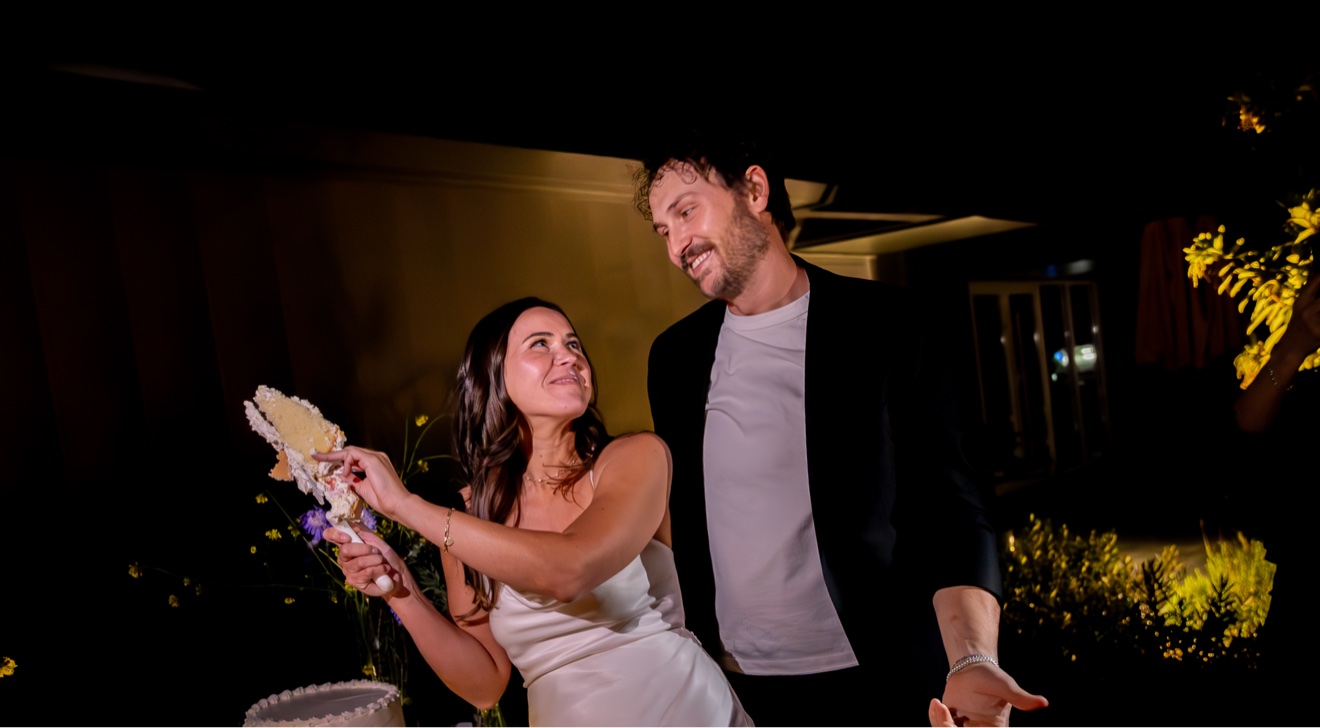 Wedding couple sharing a playful cake moment at night